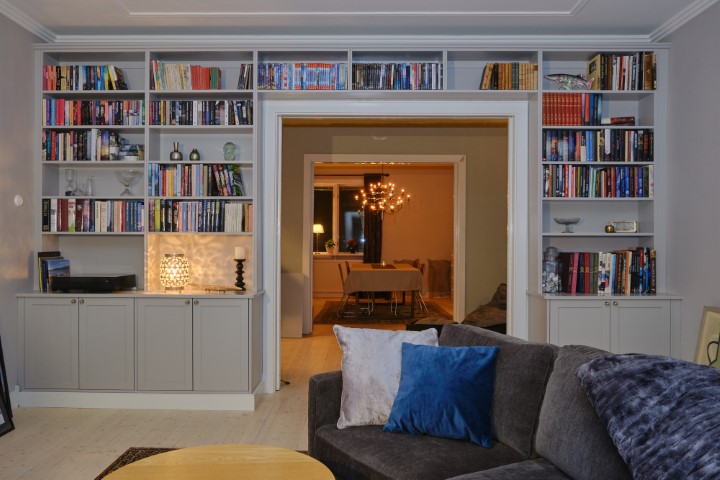 Platsbyggd grå bokhylla med bänkförvaring fylld med böcker